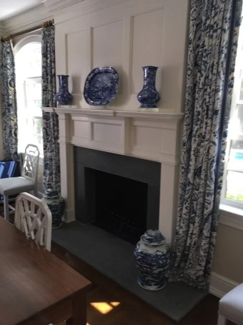 White fireplace with blue-and-white vases and patterned curtains