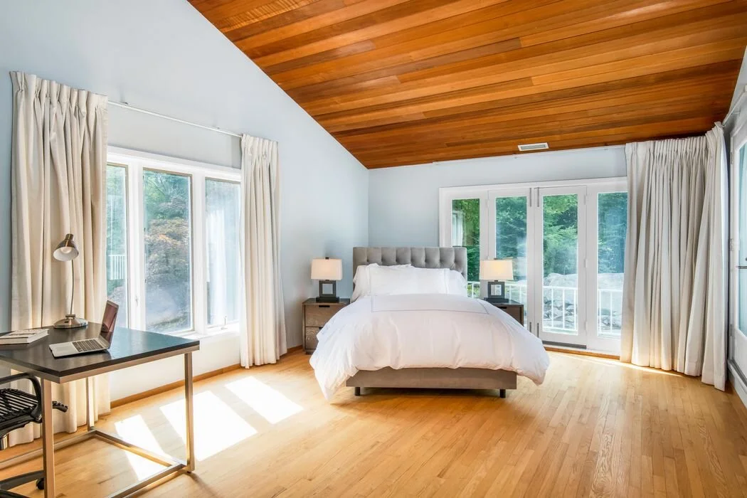 Guest bedroom with vaulted wood ceiling and white linens